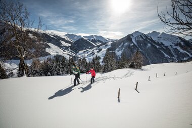 Zwei Personen in verschneiter Landschaft beim Schneeschuhwandern | © saalbach.com, Mirja Geh